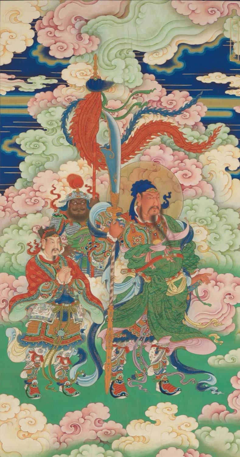 Qing hanging scroll of Guan Yu deified as Guandi, c. 1700 — a green dragon-scroll robe under a jewelled green-and-gold breastplate, a civil attendant and an armoured general standing together to one side of him amid pink and mint clouds